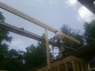 Carpenter setting a ridge beam over a new addition frame — Ice Dam Removal by Roofing Brothers in Bedrock
