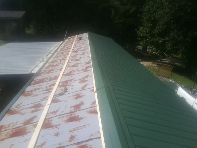 Old rusted panels beside newly installed green metal roofing — Wind Damage Roof Repair by Roofing Brothers in Bedrock
