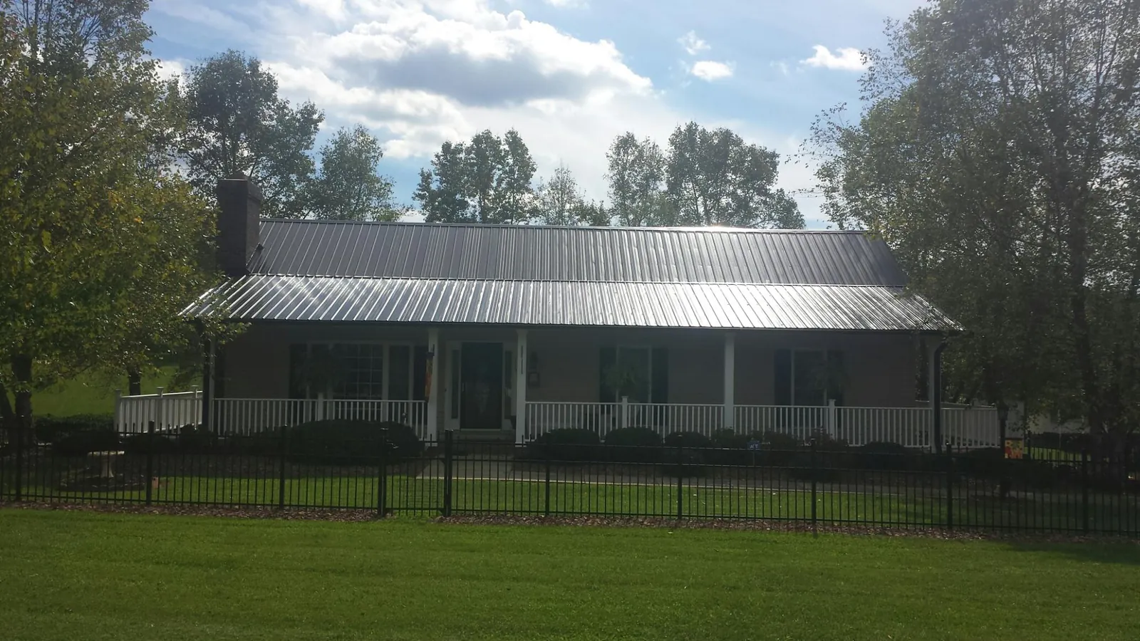 Gray metal roof on a brick ranch with a full width front porch — Gutter Guard Installation work by our crew in Bedrock